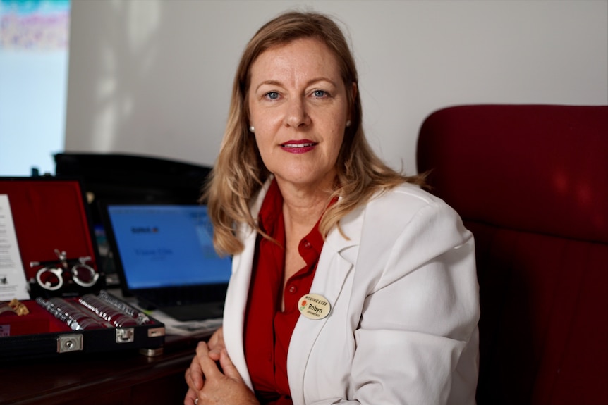 Female optometrist sitting at her desk wearing a lab coat. 