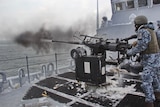 Members of the Ukrainian Navy fire a gun during naval drills on a ship.