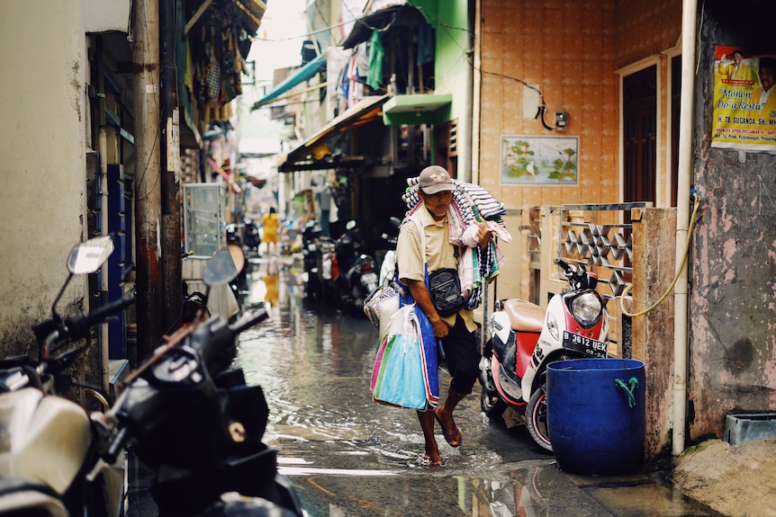 A man walking through water in the streets.