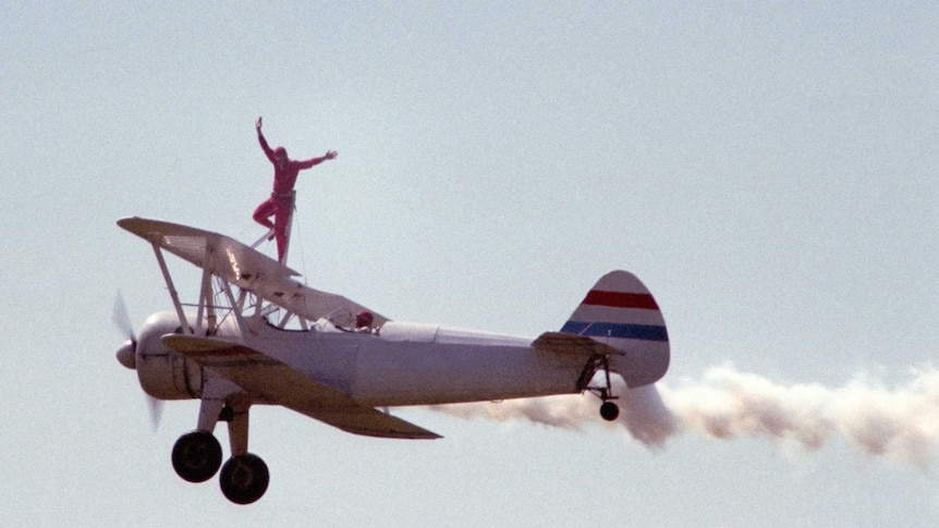 Plane flying in sky with wing walker on the wing
