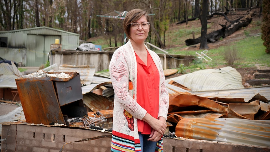 Sara Haslinger standing in front of the rubble of her Southern Highlands home which was destroyed by a bushfire