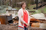 A woman standing in front of the rubble of her Southern Highlands home, which was destroyed by a bushfire.