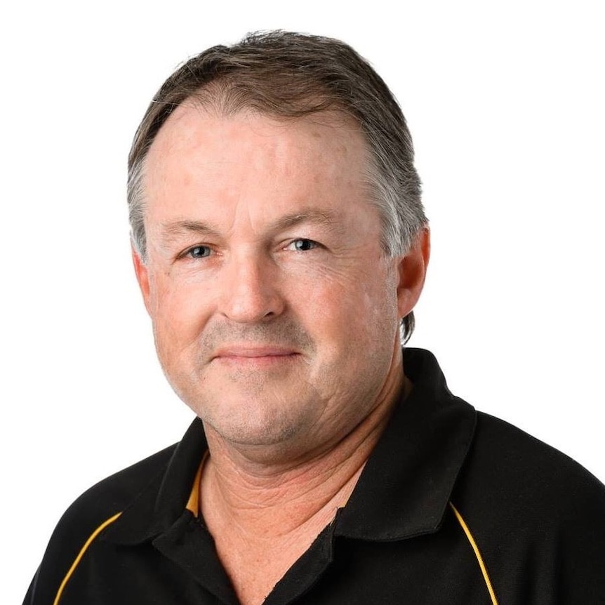 A man with grey hair and wearing a polo shirt looks at the camera.