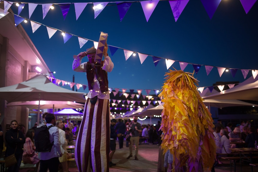 A person walking on stilts at a carnival.