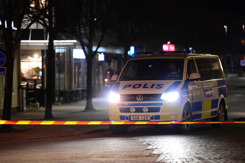 A Swedish police vehicle sits on a dark street