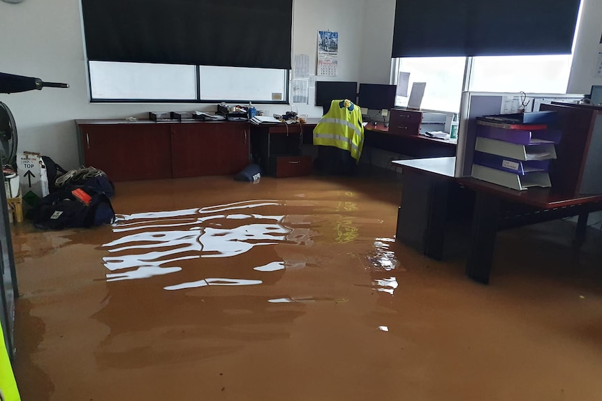 Brown water in a flooded with surrounded with office materials and high-viz jackets
