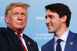 Justin Trudeau smiles and shakes hands with an unsmiling Donald Trump.