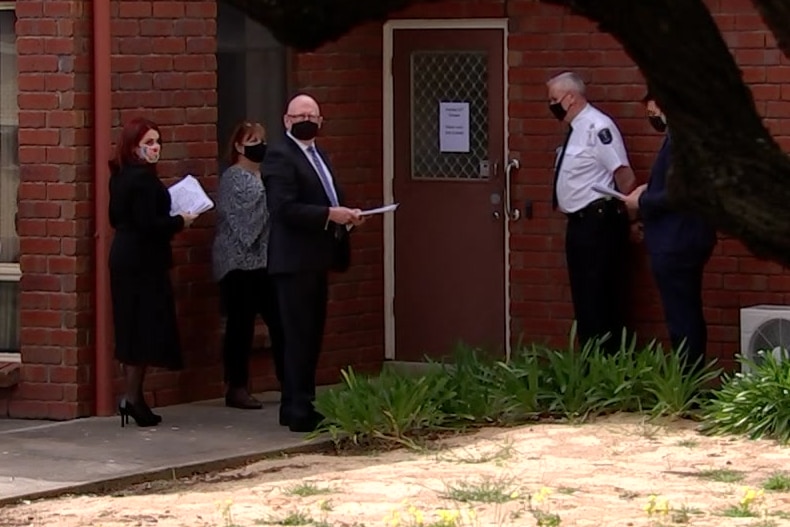 A group of people standing in front of a red brick building