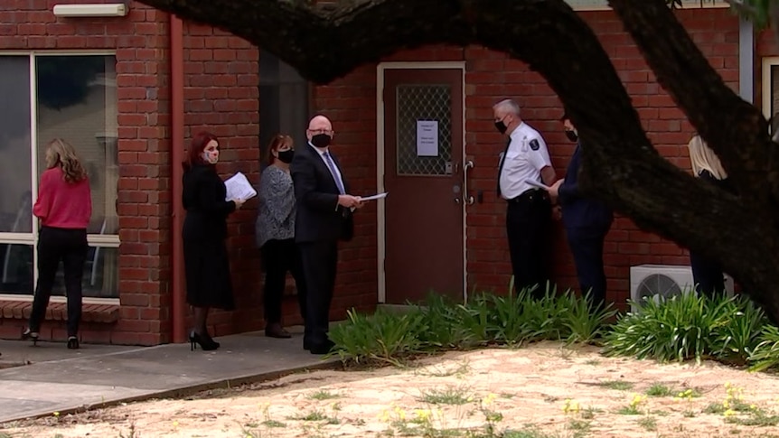 A group of people standing in front of a red brick building