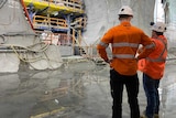 Two workers discuss the Martin Place metro rail station project, with tunnel in front of them.