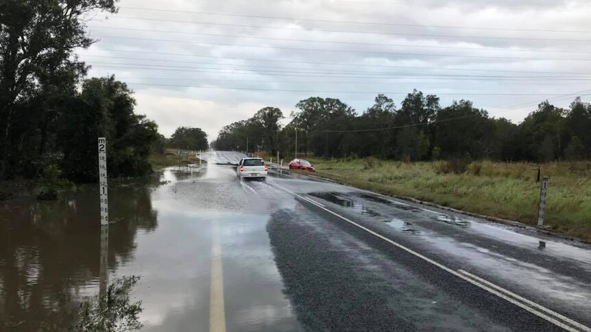 Cars drive through minor flooding in Hervey Bay along Booral Road on October 3, 2017.