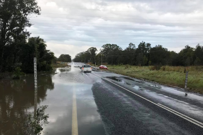 Cars drive through minor flooding in Hervey Bay along Booral Road on October 3, 2017.