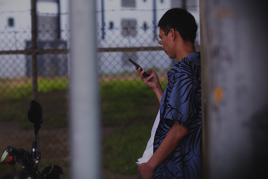 A man in a tropical patterned shirt uses his phone
