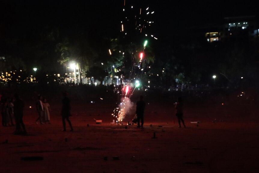 A group of people letting off fireworks on a beach