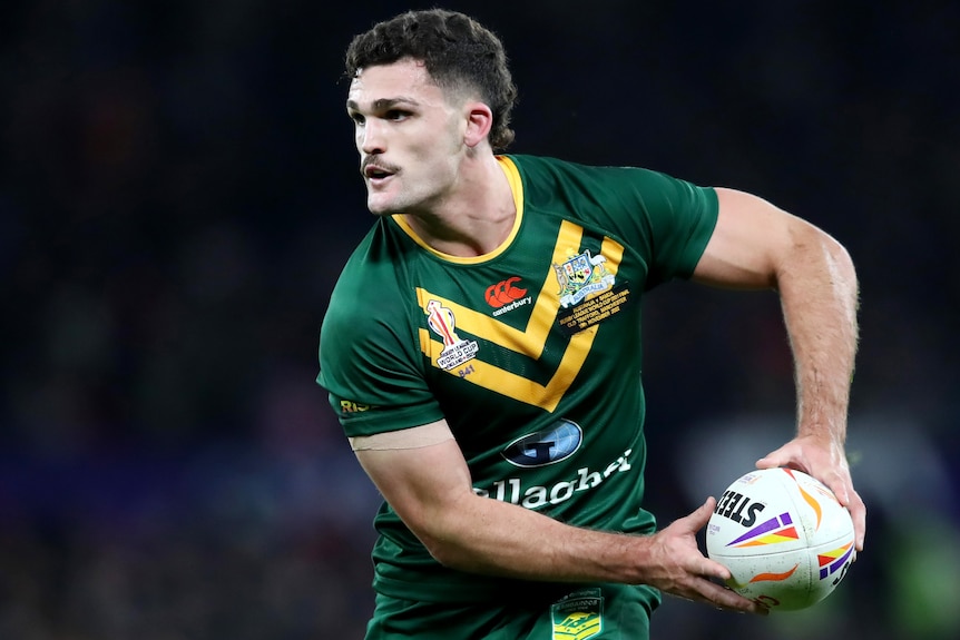 Nathan Cleary holds the ball in both hands as he plays for Australia at the 2022 men's Rugby League World Cup.