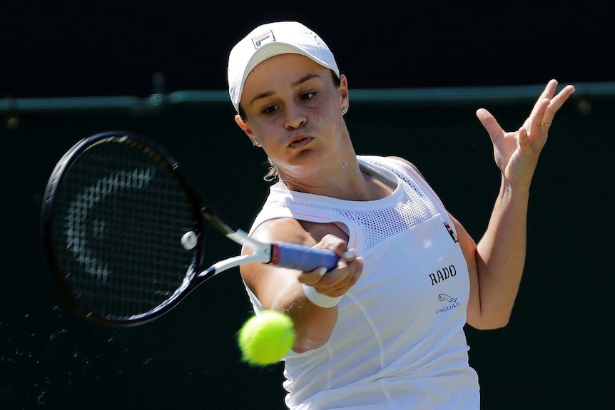 A female tennis player looks at a tennis ball as she prepares to hit it with a forehand stroke.