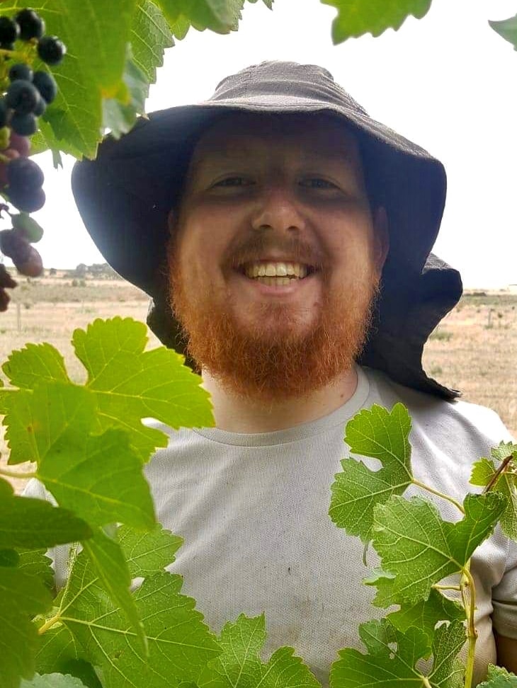 British backpacker Roan Hodgson standing in a vinyard.