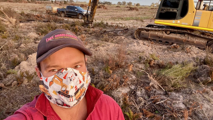 West Wimmera farmer James Hawkins in a paddock with earthmoving equipment behind him