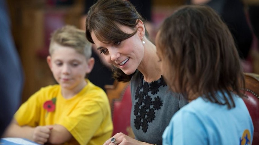 Kate Middleton speaks with two children at a table
