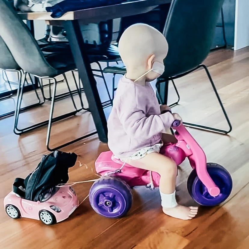 a toddler riding a trike with a makeshift trailer