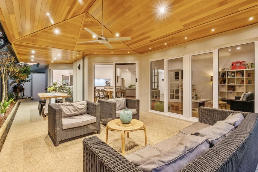 Lights illuminate an airy outdoor living space with a high wooden ceiling.