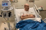 Dave Roberts sitting up in his hospital bed surrounded by equipment