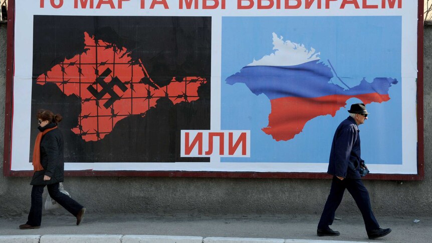 People walk past a poster in Crimea