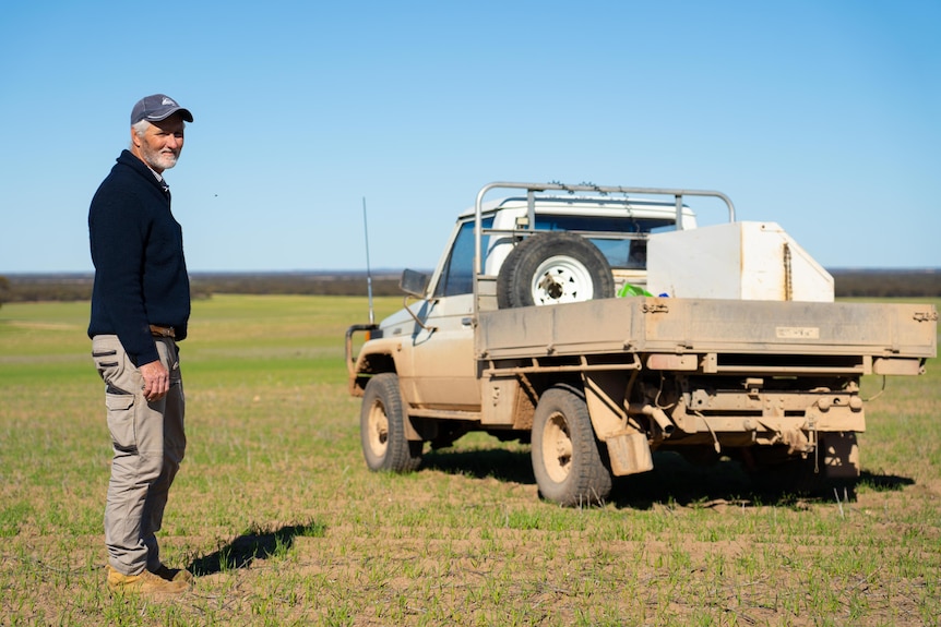 man standing next to farm truck