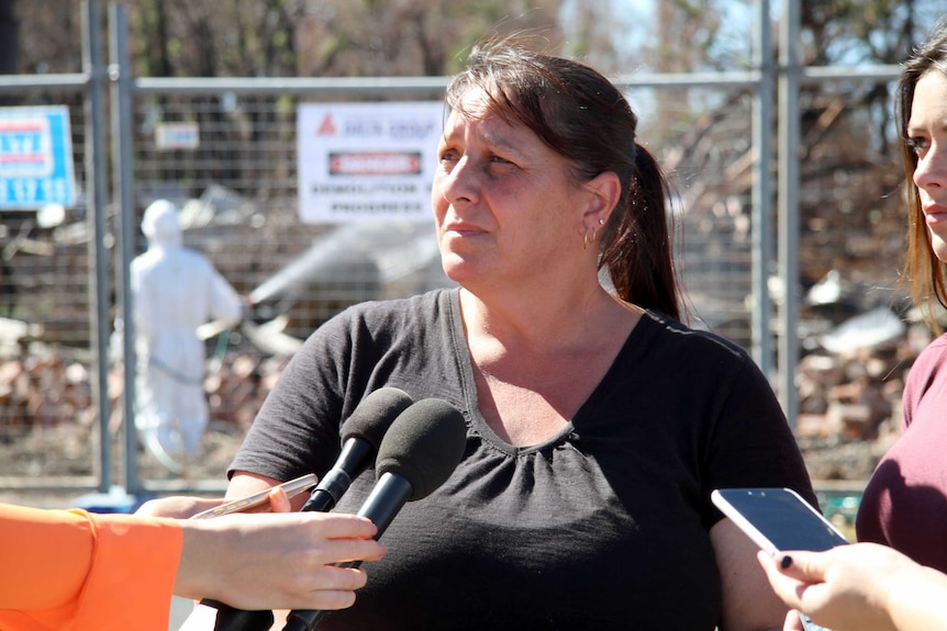 Yarloop resident Emma Reed speaks with journalists as her fire-gutted home is demolished