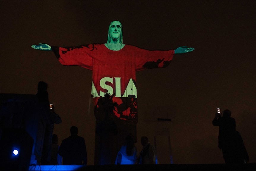 Rio's Christ the Redeemer statue is lit up in red, black and green with the word Asia written on him.