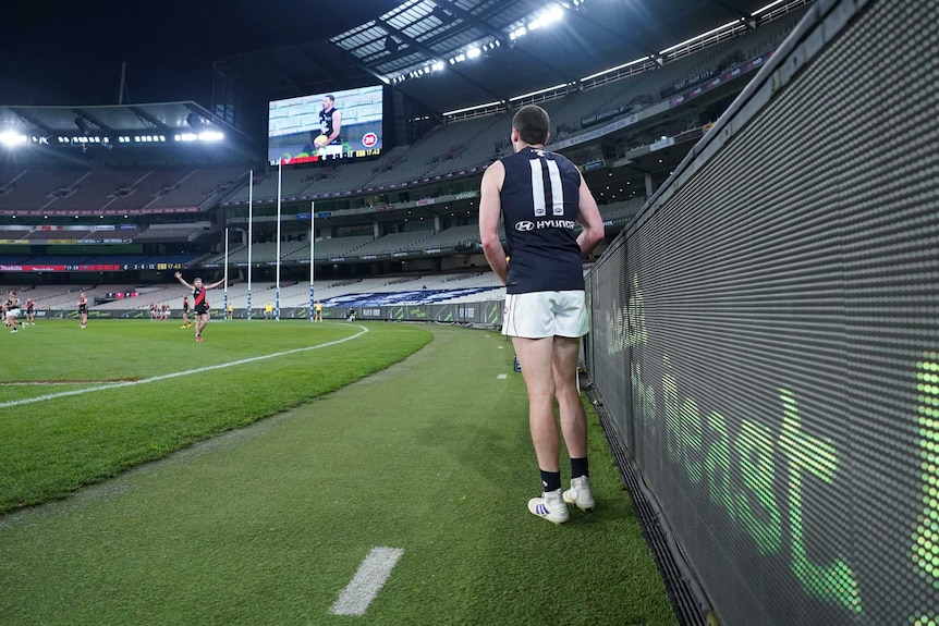 Mitch McGovern stands next to the fence as he looks towards the goalposts.