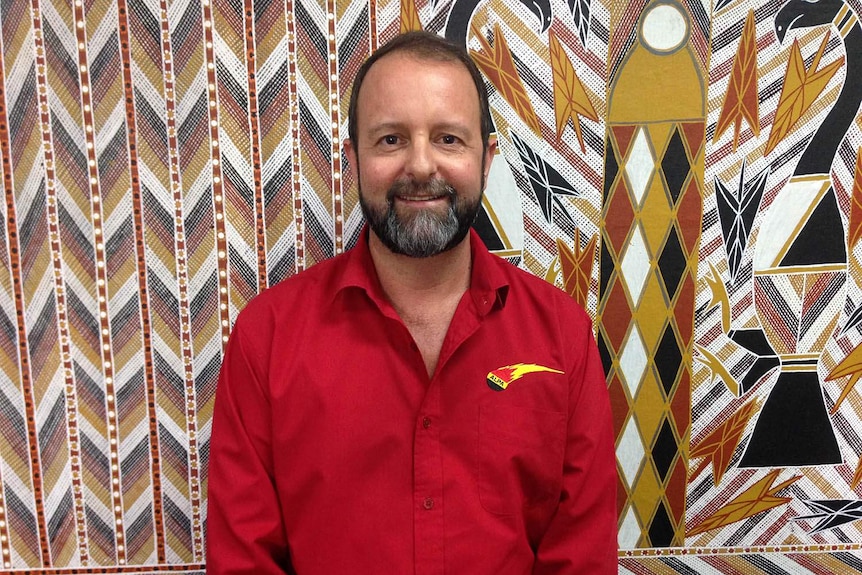 A man in front of Indigenous art