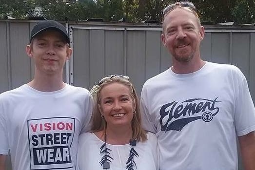 A young man and an older woman and older man pose for a photo, smiling.