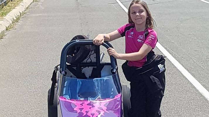 Eight-year-old Anita Board standing next to her pink and purple junior drag car on the tarmac at Perth's Kwinana Motorplex.
