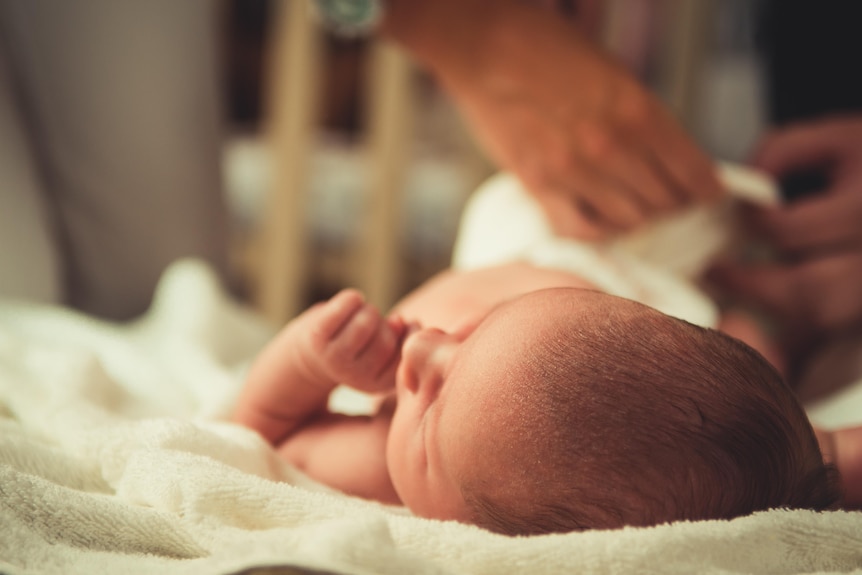 Newborn baby gets a nappy change.