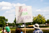A sign at a protest that says "Save Our Children".