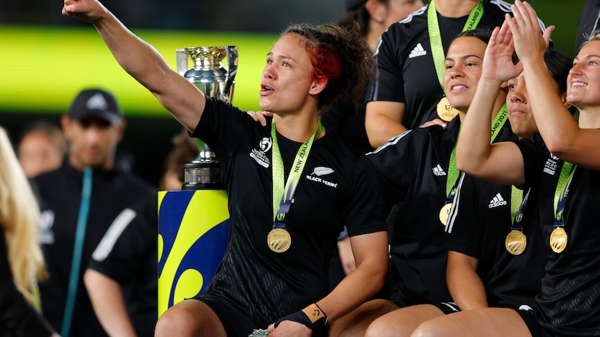 A woman points to the stands as her teammates celebrate.