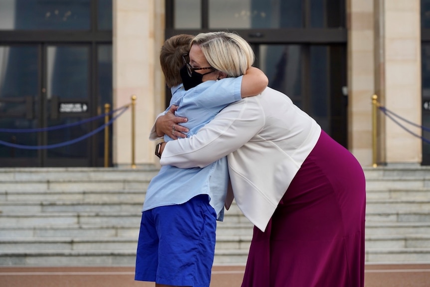 A side-on shot of Hannah Beazley hugging her son outside Parliament House in Perth.