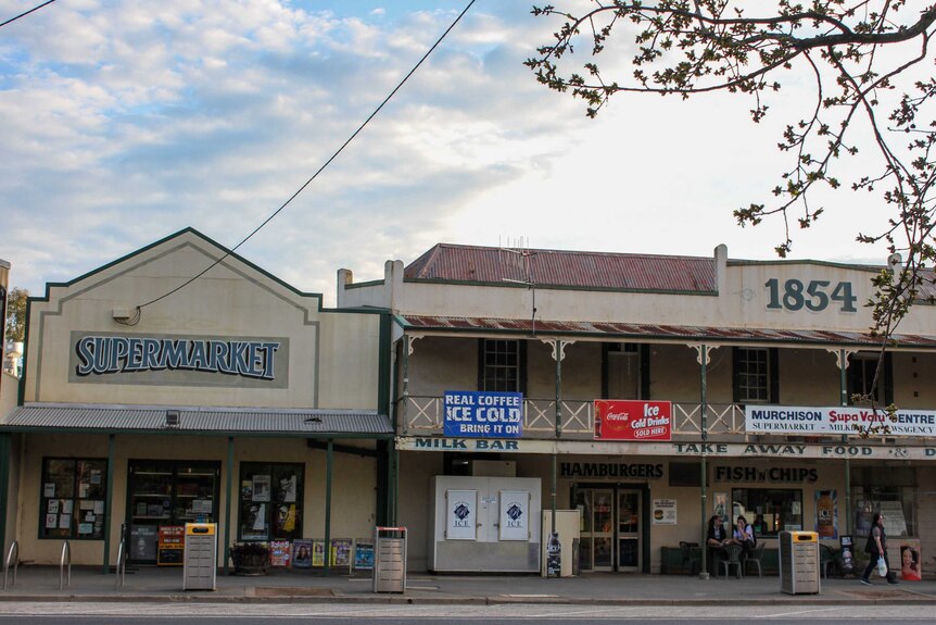 An old pub building with "1854" emblazoned across the top stands next to a building labelled "supermarket".