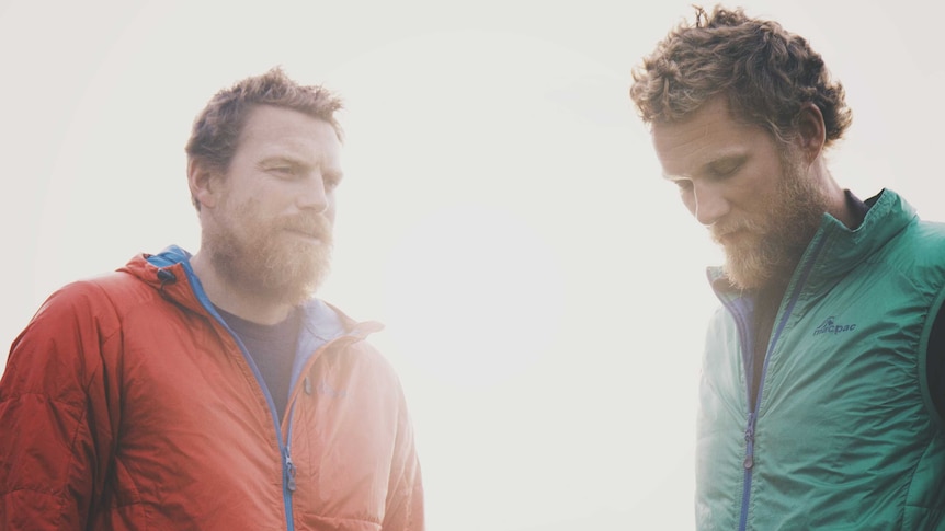 Two men with beards stand together.