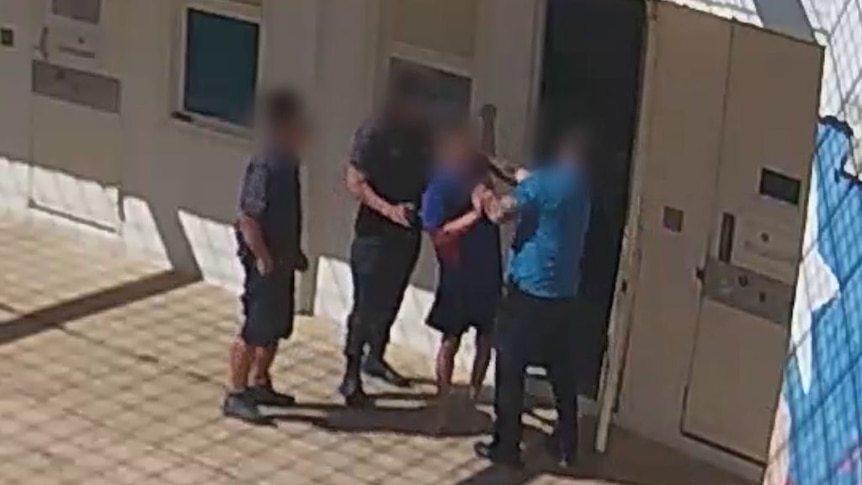 A boy is grabbed by the neck after walking out of his cell at Don Dale Youth Detention Centre