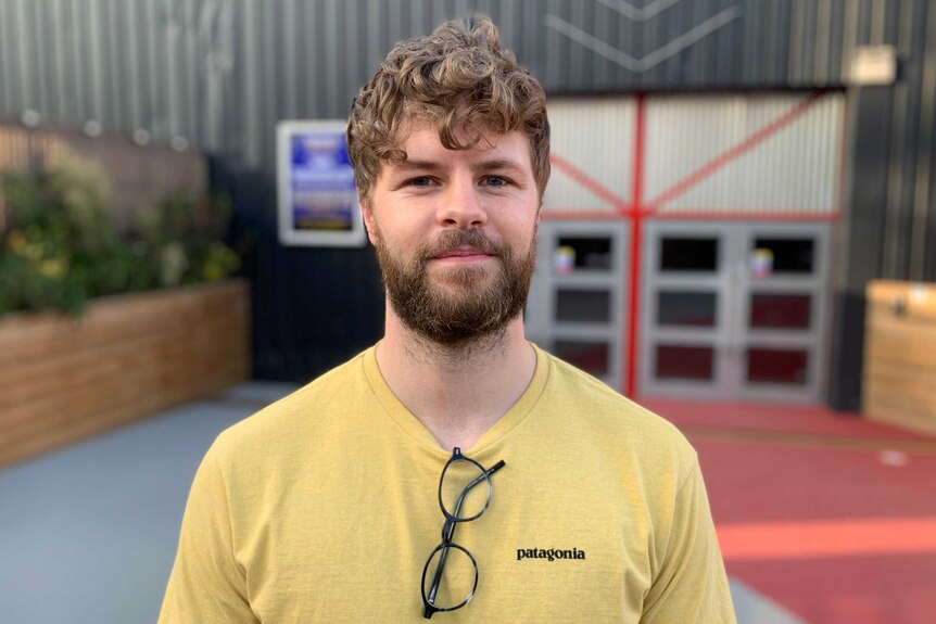 A young man in a t-shirt stands at the entrance to a theatre