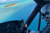 A helicopter pilot flies over water off the Central Queensland an island can be seen in the distance.
