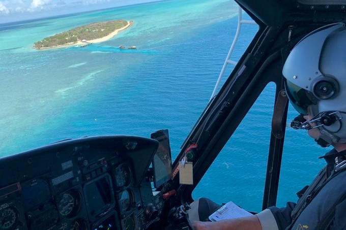 A helicopter pilot flies over water off the Central Queensland an island can be seen in the distance.