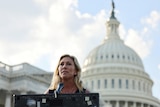 Representative Marjorie Taylor Greene stands at a lectern in front of Capitol building in the United States  