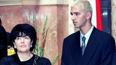 Ms Markovic, wearing dark clothing, stands beside her son Marko who is wearing a suit.