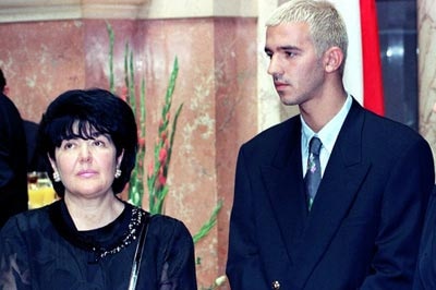 Ms Markovic, wearing dark clothing, stands beside her son Marko who is wearing a suit.