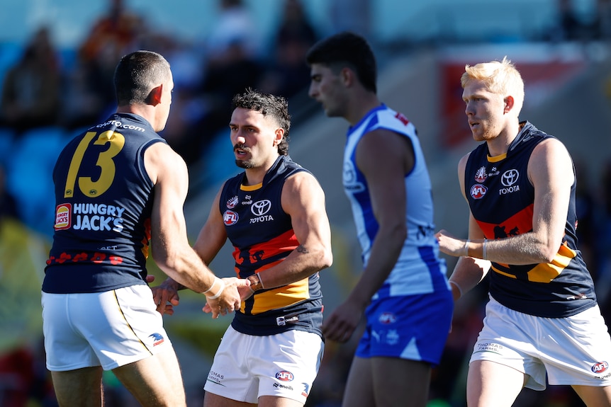 An Adelaide Crows forward clasps hands with his teammate in celebration after kicking a goal.