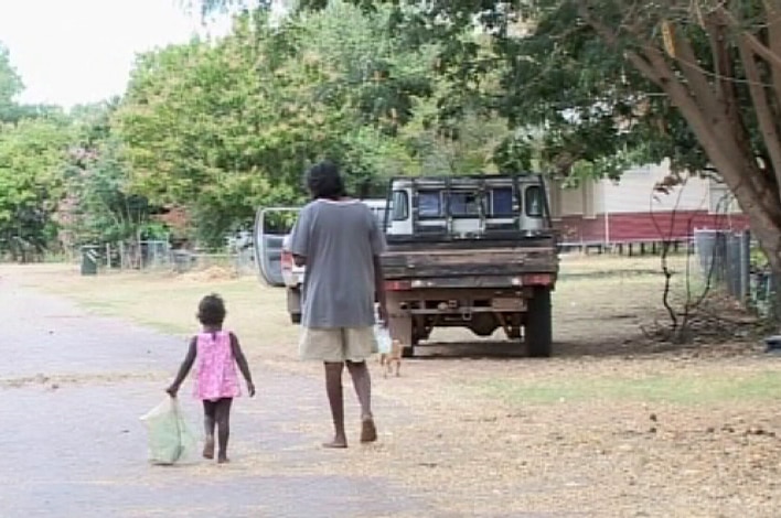 A man and a little girl walking along a road in Oombulgurri before settlement demolished