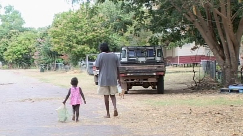 A man and a little girl walking along a road in Oombulgurri before the settlement was closed.